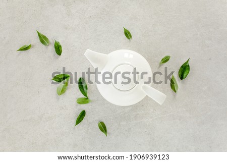 Herbal tea in a white teapot, with green tea leaves. Flat lay, top view. Tea concept