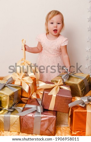 Little cute girl in pink dress and lots of gift boxes