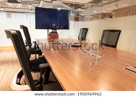 meeting room with clear acrylic sheet separates the center on the conference table to prevent COVID-19 and face shield on the table.