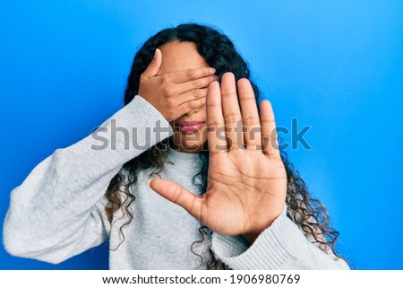 Young latin woman wearing casual clothes covering eyes with hands and doing stop gesture with sad and fear expression. embarrassed and negative concept. 
