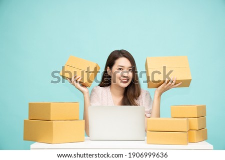 Young asian woman startup small business freelance holding parcel box and computer laptop and sitting isolated on green background, Online marketing packing box delivery concept Royalty-Free Stock Photo #1906999636