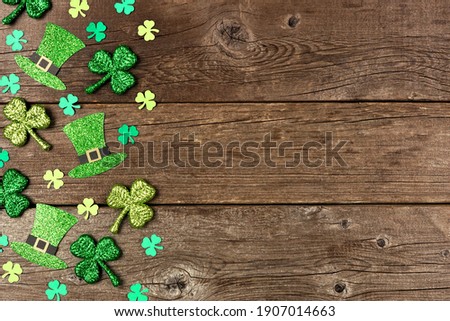 St Patricks Day shamrock and leprechaun hat side border. Above view over a rustic wood background with copy space.