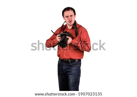 Portrait of young photographer preparing to take some pictures. He wears red shirt and blue jeans. Isolated, white background.