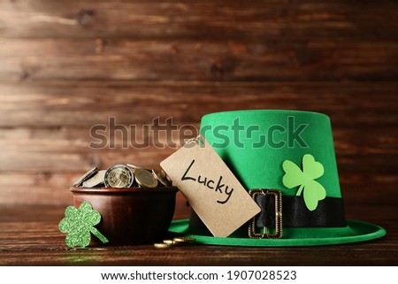 St.Patrick's Day. Green hat with coins in bowl and word Lucky on brown wooden table
