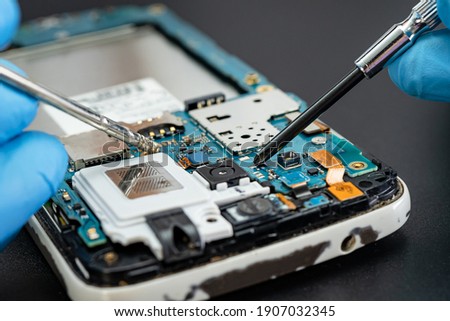Technician repairing inside of mobile phone by soldering iron. Integrated Circuit. the concept of data, hardware, technology. Royalty-Free Stock Photo #1907032345
