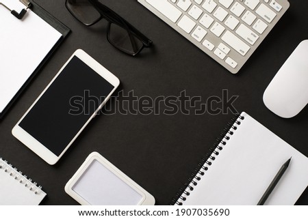 Flat lay top above overhead view photo of office of items with planner keyboard eyewear cellphone with blank empty space in center for design text isolated black backdrop