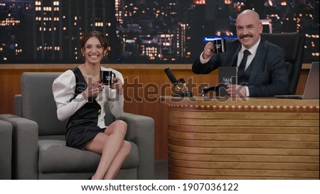 Late-night talk show host having a conversation with celebrity guest in a studio. TV broadcast style show Royalty-Free Stock Photo #1907036122