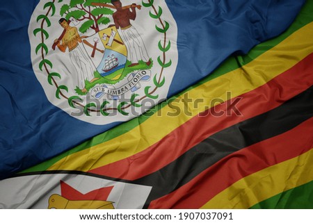 waving colorful flag of zimbabwe and national flag of belize. macro