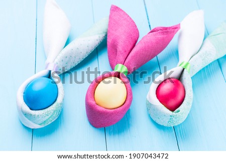 Easter eggs and the shape of rabbit ears, on a blue wooden background, selective focus, tinted image