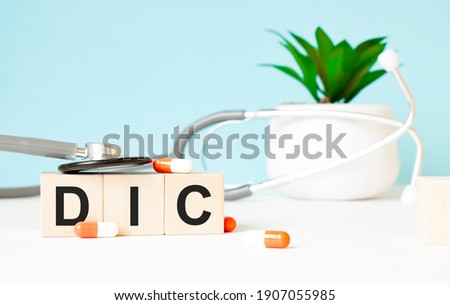 The word dic is written on wooden cubes near a stethoscope on a wooden background. Medical concept Royalty-Free Stock Photo #1907055985