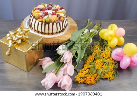 Birthday cake, presents, colorful balloons as flowers on grey wwoden background, holiday concept, closeup