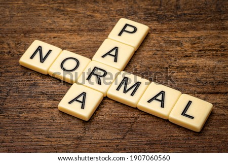 paranormal crossword in ivory letter tiles against rustic weathered wood, supernatural and unexplained phenomena Royalty-Free Stock Photo #1907060560