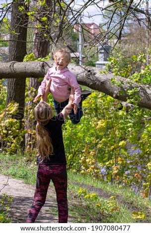 happy teenage girl catches little sister from tree