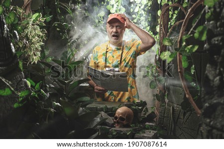 Funny scared tourist lost in the tropical jungle, he is holding a map Royalty-Free Stock Photo #1907087614