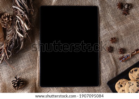 Tablet with black mockup, biscuit, and different spices on burlap. Culinary blog, recipe template, online cooking courses. Top view. Flat lay.
