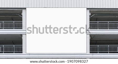 large billboard mockup of white colour located between grey balconies in building under bright summer sunlight