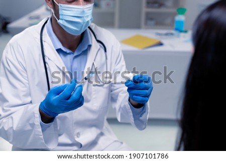 Caucasian male doctor wearing face mask and gloves preparing vaccine for patient. healthcare and hygiene during coronavirus covid 19 pandemic. vaccine