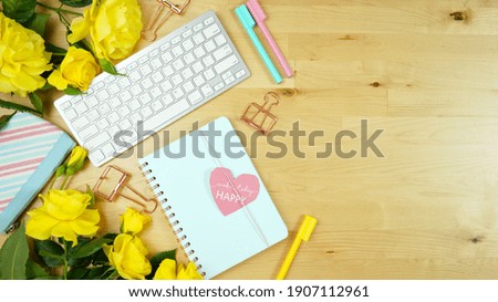 Modern feminine pink, blue and yellow theme desktop workspace with yellow roses on stylish pale wood background. Top view blog hero header creative composition flat lay. Negative copy space.