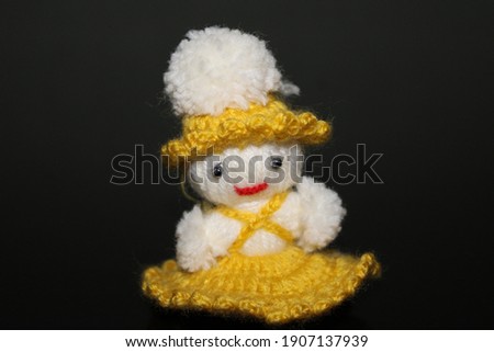 knitted small handmade doll on black background. angel figure