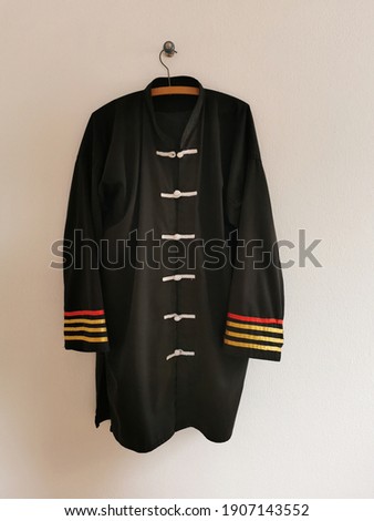 A black graduated kung fu suit hangs on the wall.