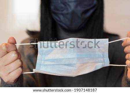 Woman using protective face mask and holding a second mask to use