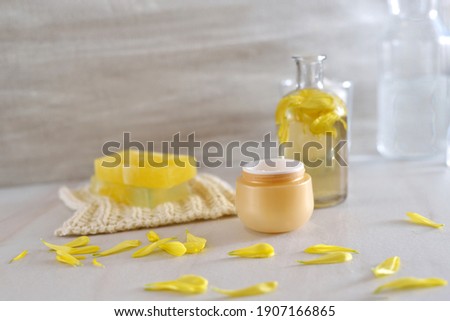 Beautiful beauty composition of cosmetic products.  spa setting for wellness center.  Jar with face cream with calendula, chrysanthemum extract.
petals of calendula, chrysanthemum. Selective focus

