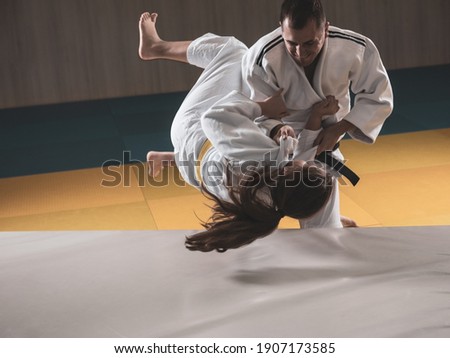 Adult black belt judoka demonstrating morote seoi nage technique on young female student Royalty-Free Stock Photo #1907173585