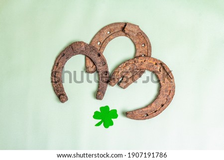 Badly worn horseshoes with a felt clover leaf. Good luck symbol, St.Patrick's day concept. Light green vinyl background