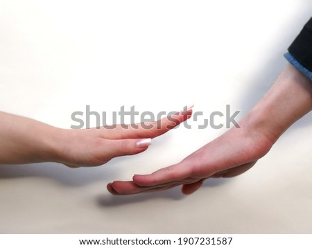 Woman's hand above man's hand in harmonious appeasement movement in white background. Concept of harmony and calming down. Idea of soft power of woman. Domination of quiet confidence. Stop violence