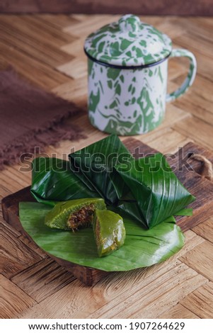 Traditional cake from Indonesia called Kue Bugis wrapped in banana leaves and taste sweet on a wood tray and chevron pattern wood textured table