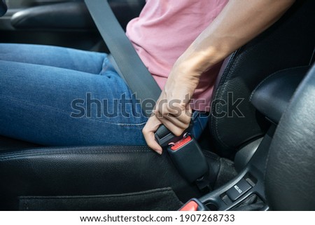 woman hand fastening a seatbelt in the car, Cropped image of a woman sitting in car and putting on her seat belt, Safe driving concept. Royalty-Free Stock Photo #1907268733