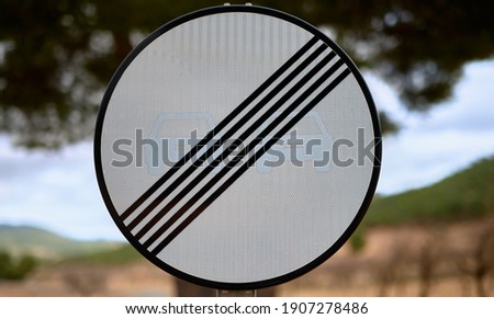 detail of a no overtaking traffic sign with a blue sky and trees in the background