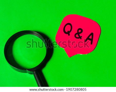Q and A concept.Top view red bubble speech written Q and A with magnifying glass isolated on green background.