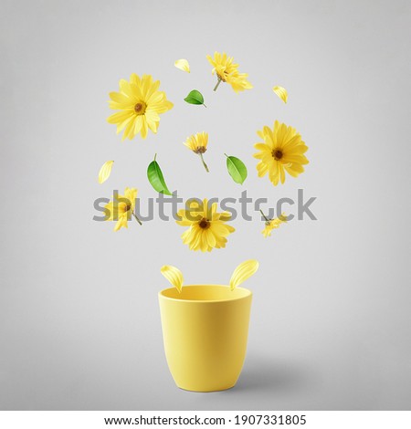 Yellow cup with flying yellow flowers on a gray background. The concept of spring.  Royalty-Free Stock Photo #1907331805