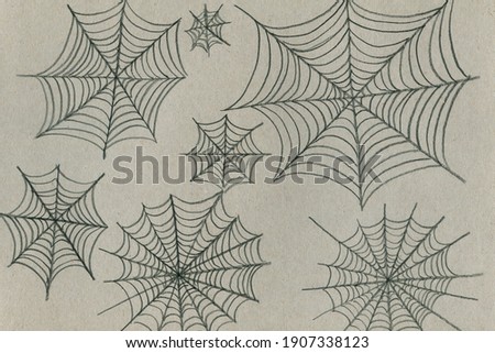 Hand-drawn with a simple pencil on a gray cardboard web of different sizes. Imitation of a child's drawing of a small and large spider web.