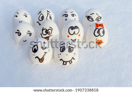 Chicken egg with a funny painted face in the snow.