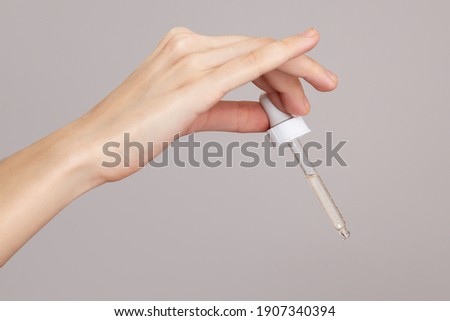 Hands of a woman holding an eyerdropper with fluid Royalty-Free Stock Photo #1907340394