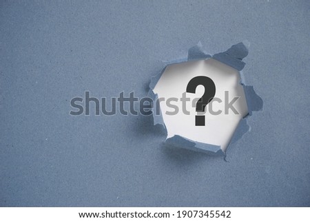 Torn grey paper with question mark. Question mark concept.                                Royalty-Free Stock Photo #1907345542