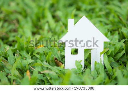 House white paper cut concept in green field background