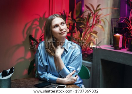 Woman sitting in a cafe at a table with a dreamy look