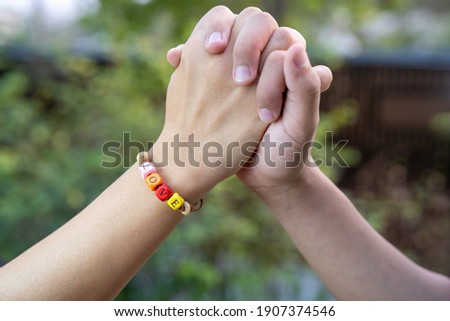 Closeup of couple making heart shape with hands, Love word on women Bead bracelet, Valentine concept.