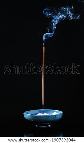 Incense stick smoldering in holder on black background Royalty-Free Stock Photo #1907393044