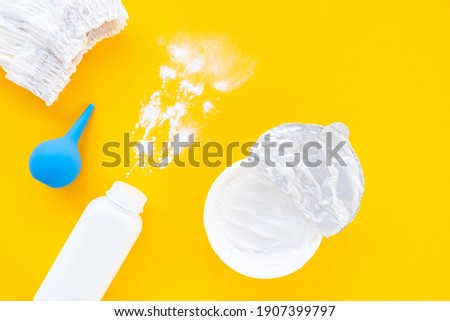 Set of children's cosmetics on a yellow background, top view, copy space, mockup. Baby hygiene, trendy minimalistic background. Flat lay composition diaper, powder, cream.