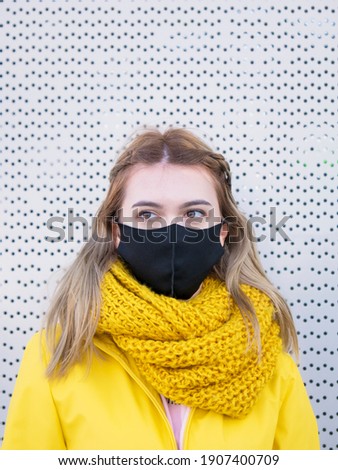 Woman wear yellow coat and protective mask on street of city Wearing in colors 2021 year illumination ultimate gray People scared about future.  Yellow and gray colors. covid-19