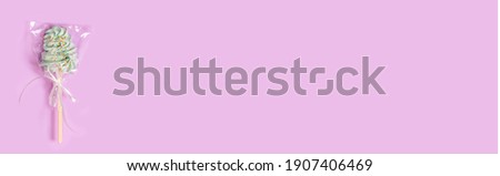 Sweet lollipop in a transparent wrapper on a gentle pastel pink background with copy space