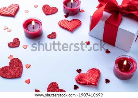 Love background: Valentines day red hearts, romantic gift box, candle on white table. Romantic message template with copy space