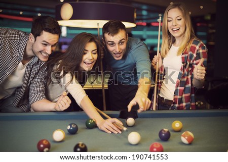 Friends cheering while their friend aiming for billiards ball Royalty-Free Stock Photo #190741553