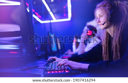 Streamer young woman rejoices in victory professional gamer playing online games computer with headphones, neon color.
