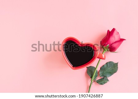 Valentine's Day background. Heart shaped cup of black coffee and rose on pastel pink background. Valentines day concept. Flat lay, top view, copy space