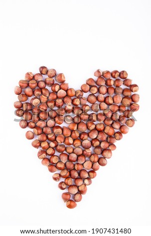 healthy hazelnuts in heart shape on white background
